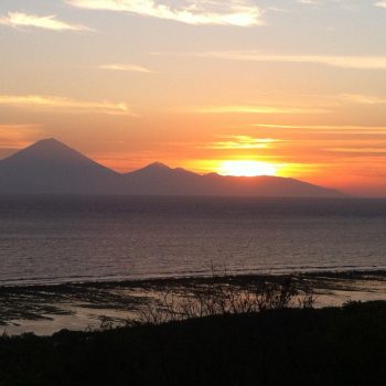 De zon zakt achter de Balinese vulkanen weg